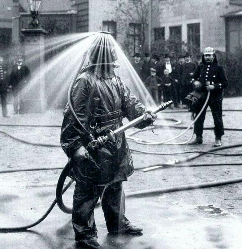 A 19th century firefighter demonstrating a helmet eqipped with multiple water nozzles to soak down the area around him.