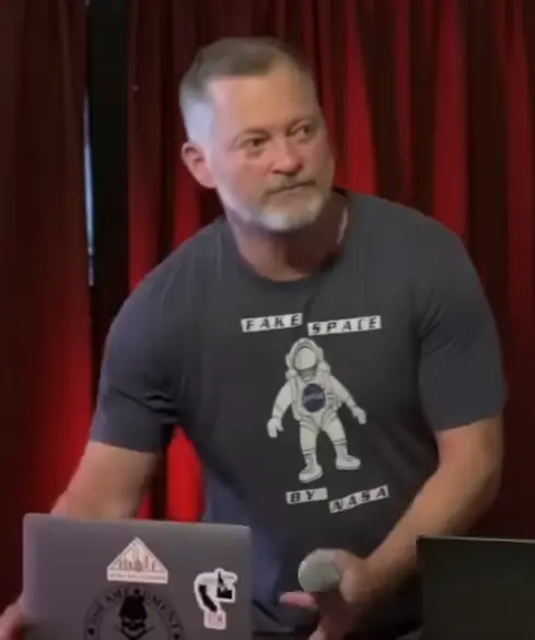 screencap of Mark Fitzpatrick wearing a t-shirt that says "fake space by NASA"