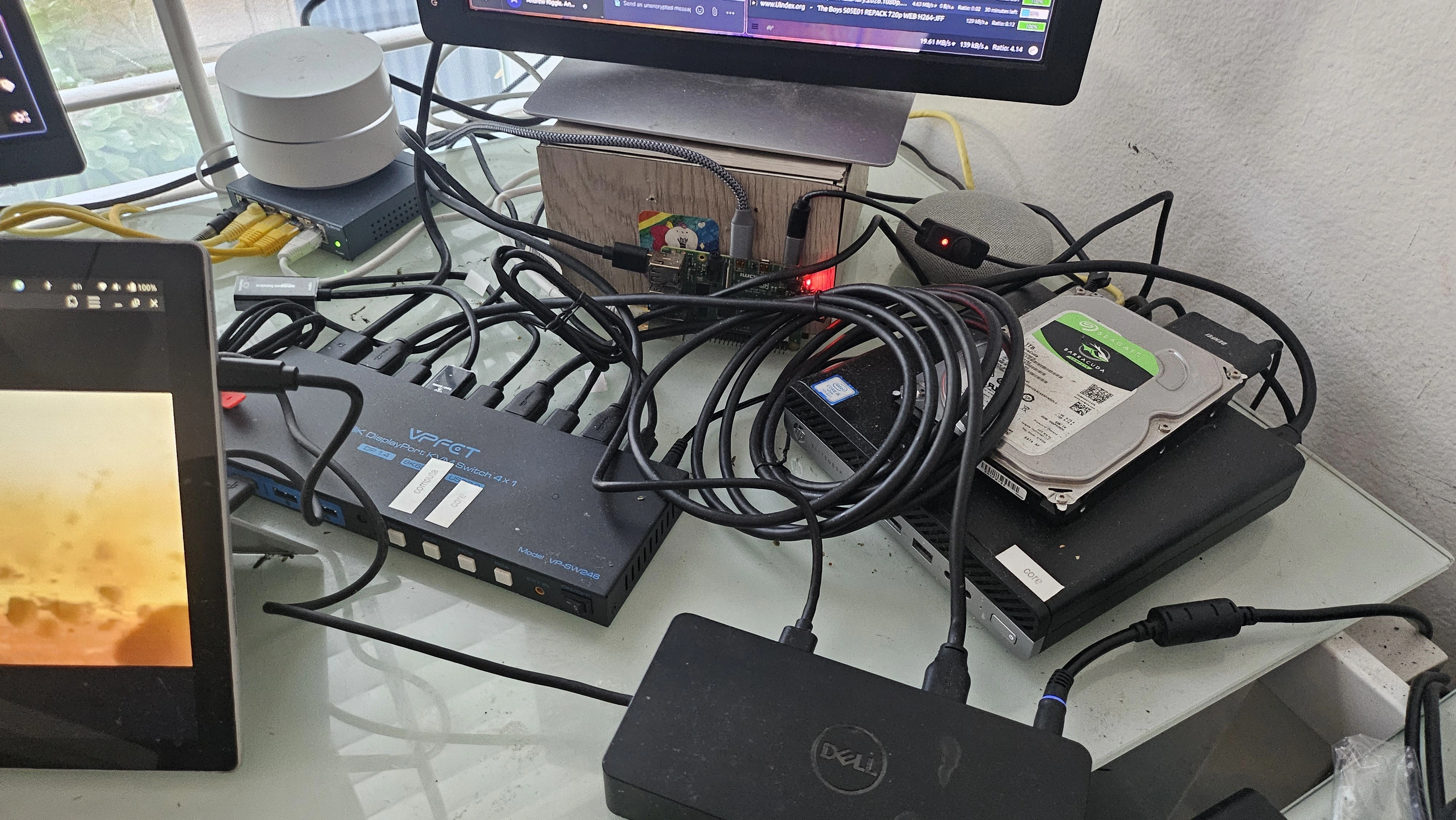 picture of a raspberrypi, switch, HP elite desk, KVM and mess of cables on a desk