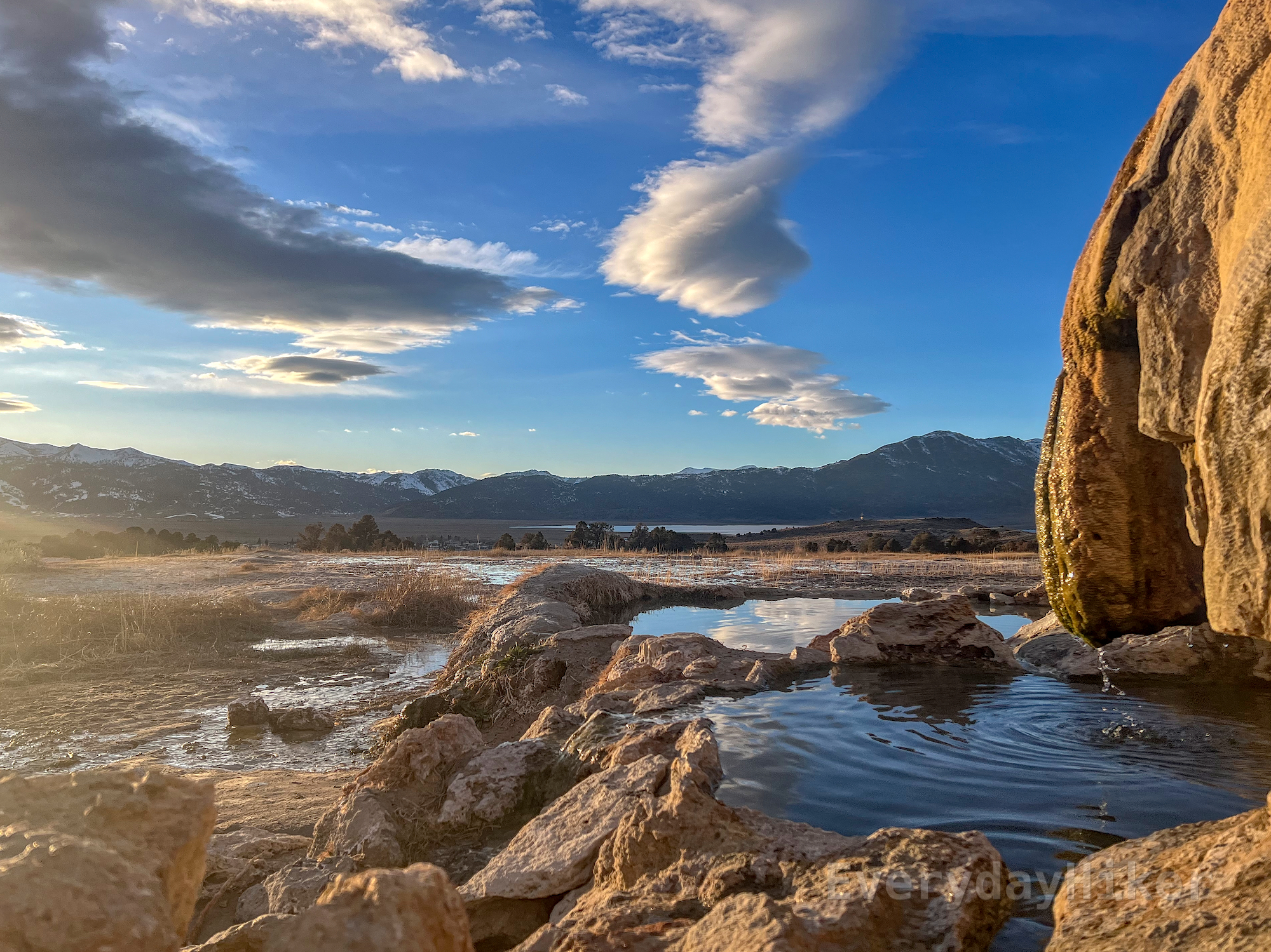 Two of the three side by side soaking pools may be seen at the upper area of the hot springs, lit up by late afternoon sun with a view of some of the Sierra mountains in the distance. Other pools may also be found around the area.
