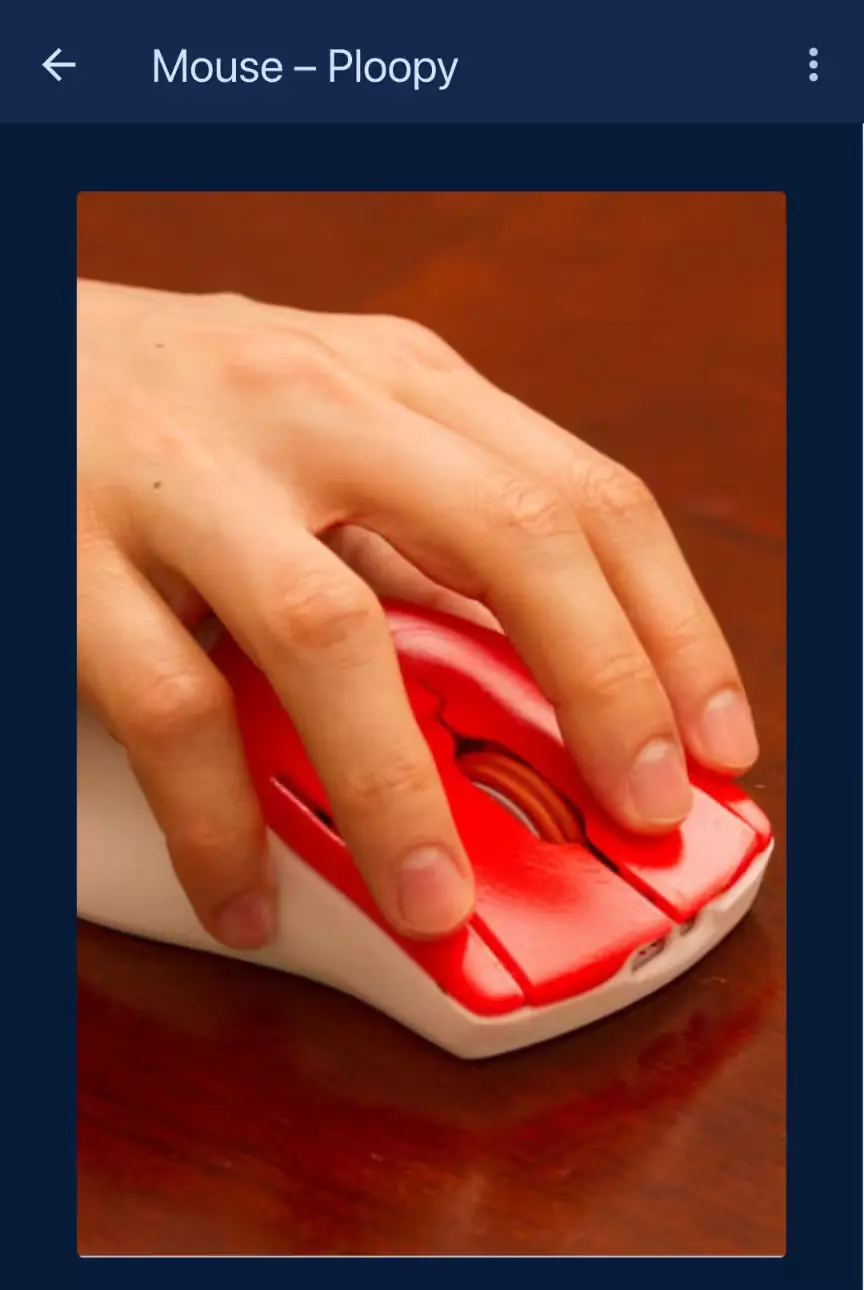 an image of a person's hand on a Ploopy mouse, with the middle finger on the left click button, and the ring finger on the right click button.
